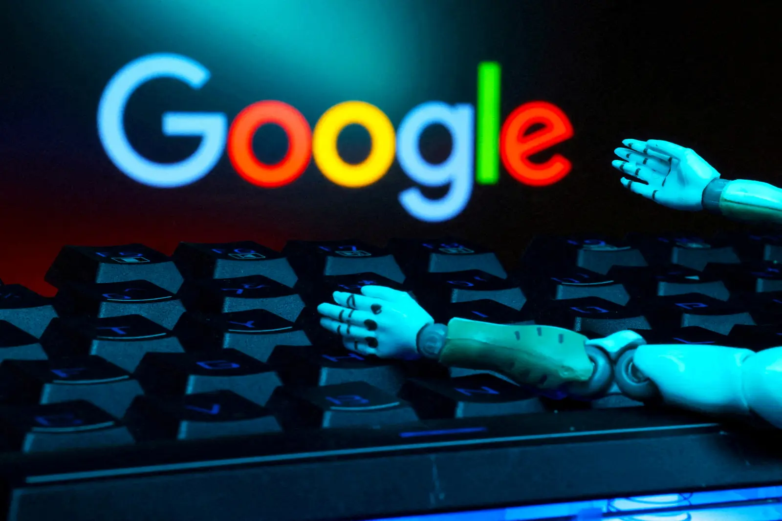 صورة مركبة تظهر شعار «غوغل» ويدي روبوت آلي فوق لوحة مفاتيح جهاز كمبيوتر